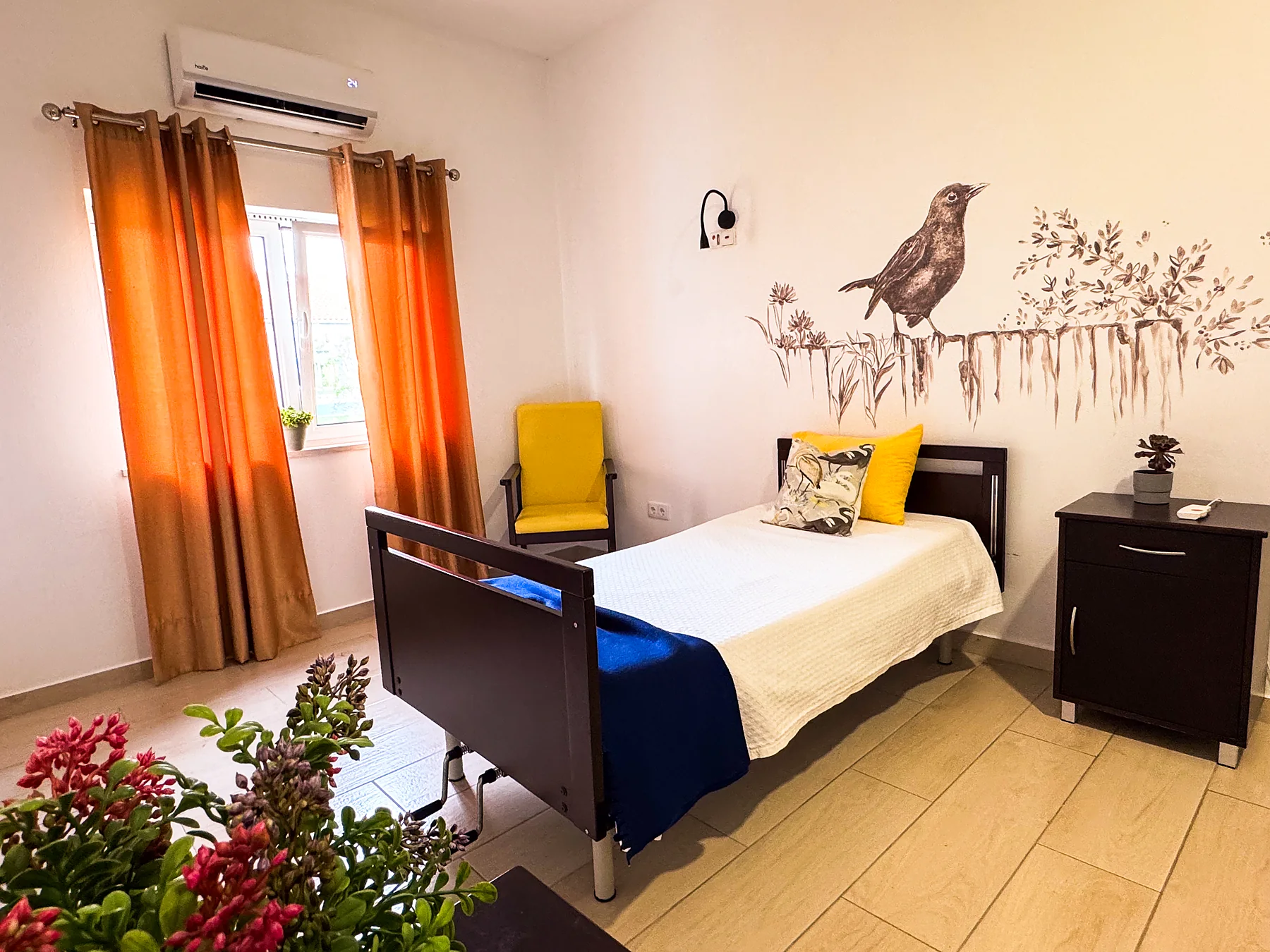 Quarto individual com cadeirão amarelo junto à janela