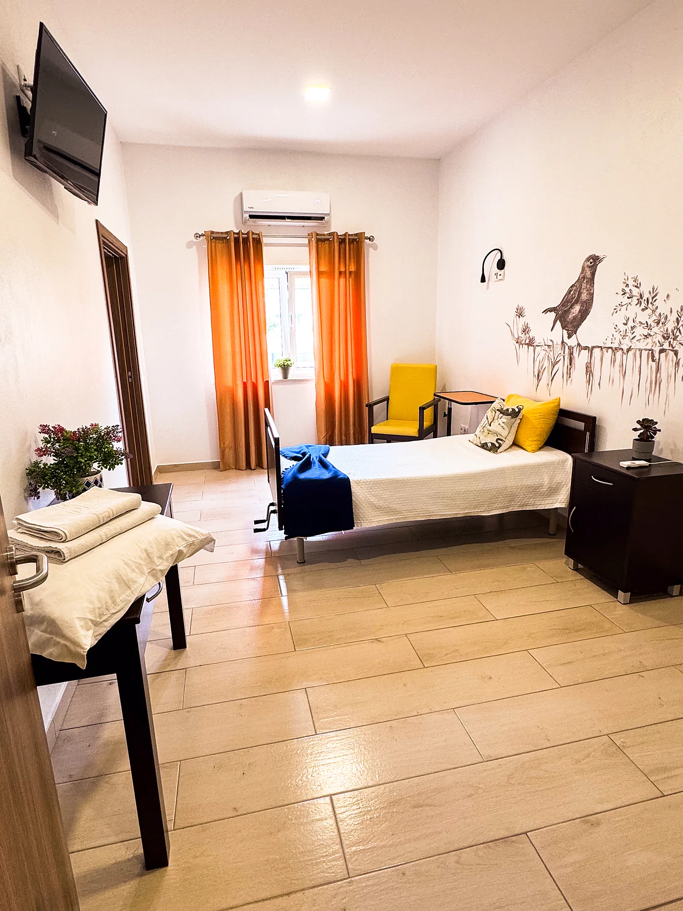 Quarto individual com cama articulada, televisão e roupa de cama preparada